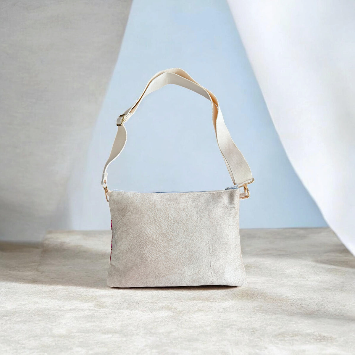 Back of Sabaleh Crossbody showing cream velvet fabric and an adjustable cream strap with gold-tone hardware.