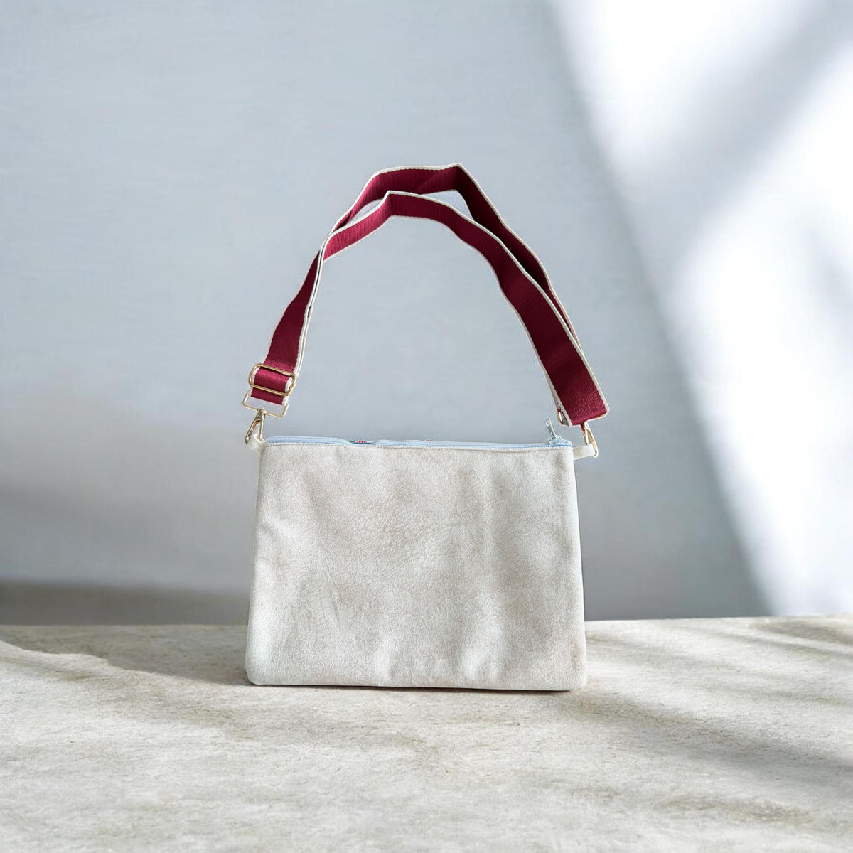 Cream velvet back of Cypress Tatreez Crossbody with burgundy adjustable strap and gold hardware.