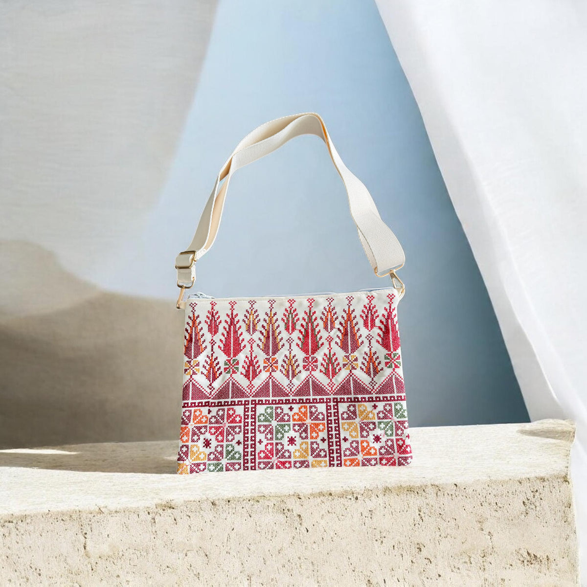 Front of Cypress Tatreez Crossbody with cream strap, red cypress motifs and multicolored geometric panels.