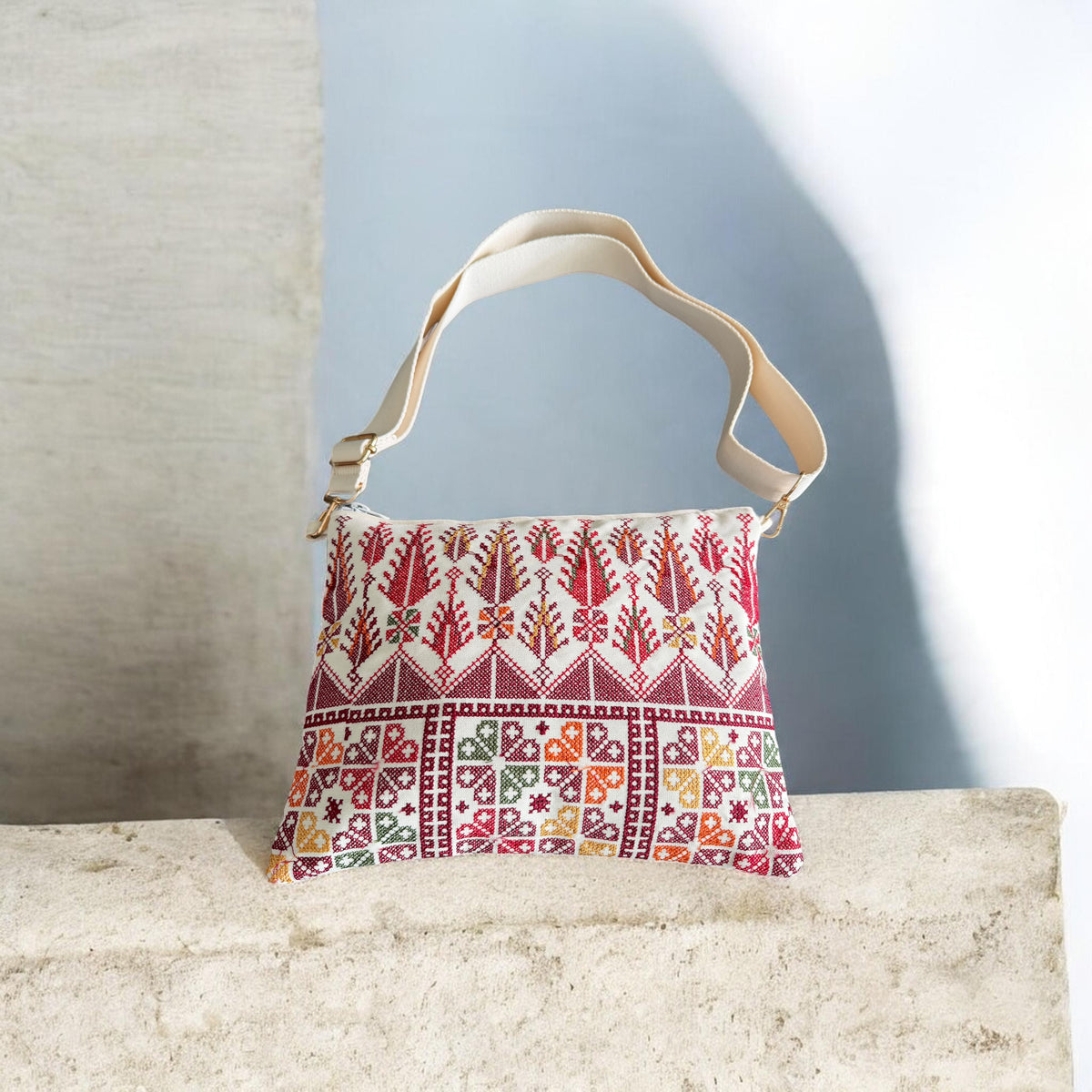 Cypress Tatreez Crossbody with cream strap, upright red cypress motifs and multicolored geometric panels.