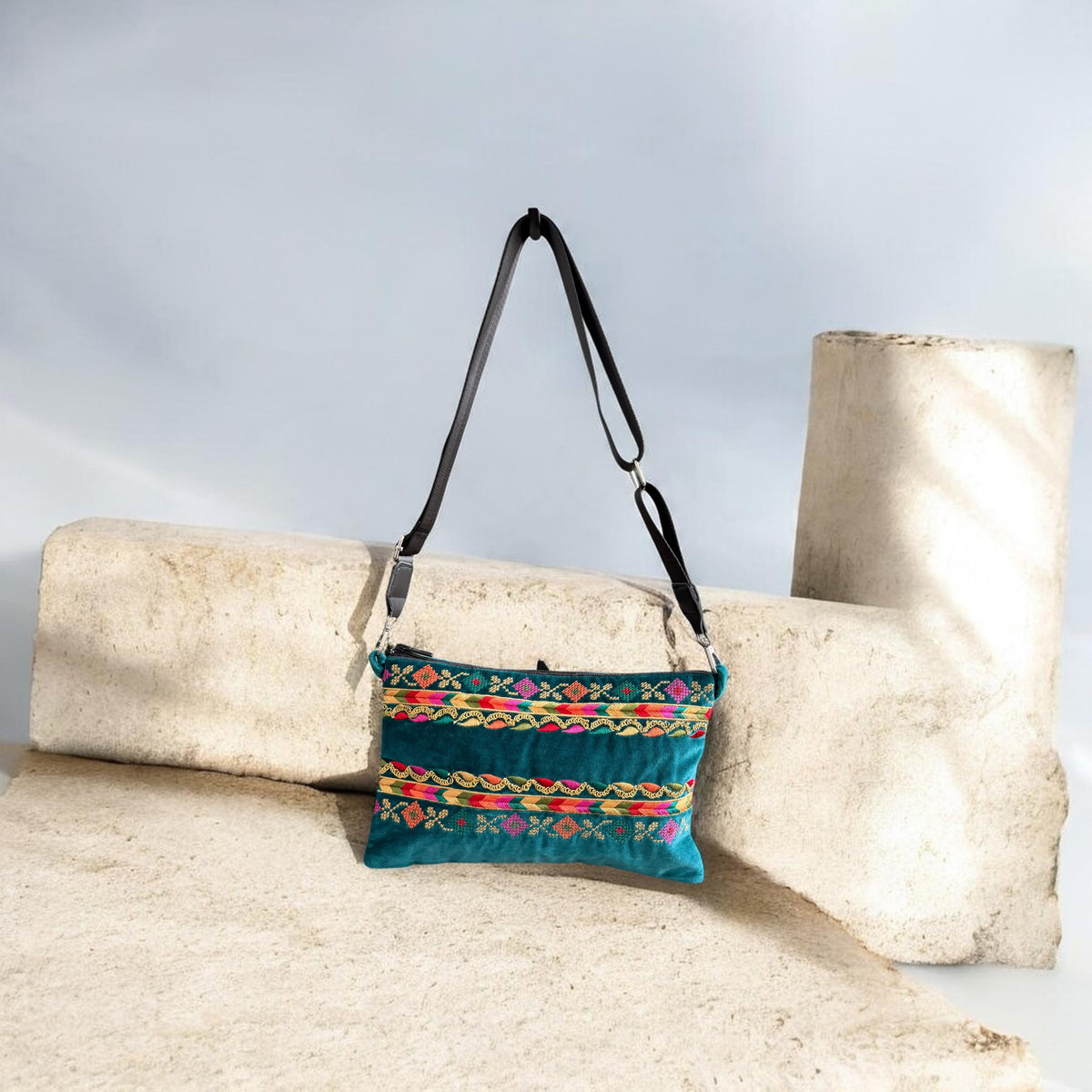 Alwan AlTurath Crossbody in green velvet hanging, showing its embroidered  tatreez and black strap with silver hardware
