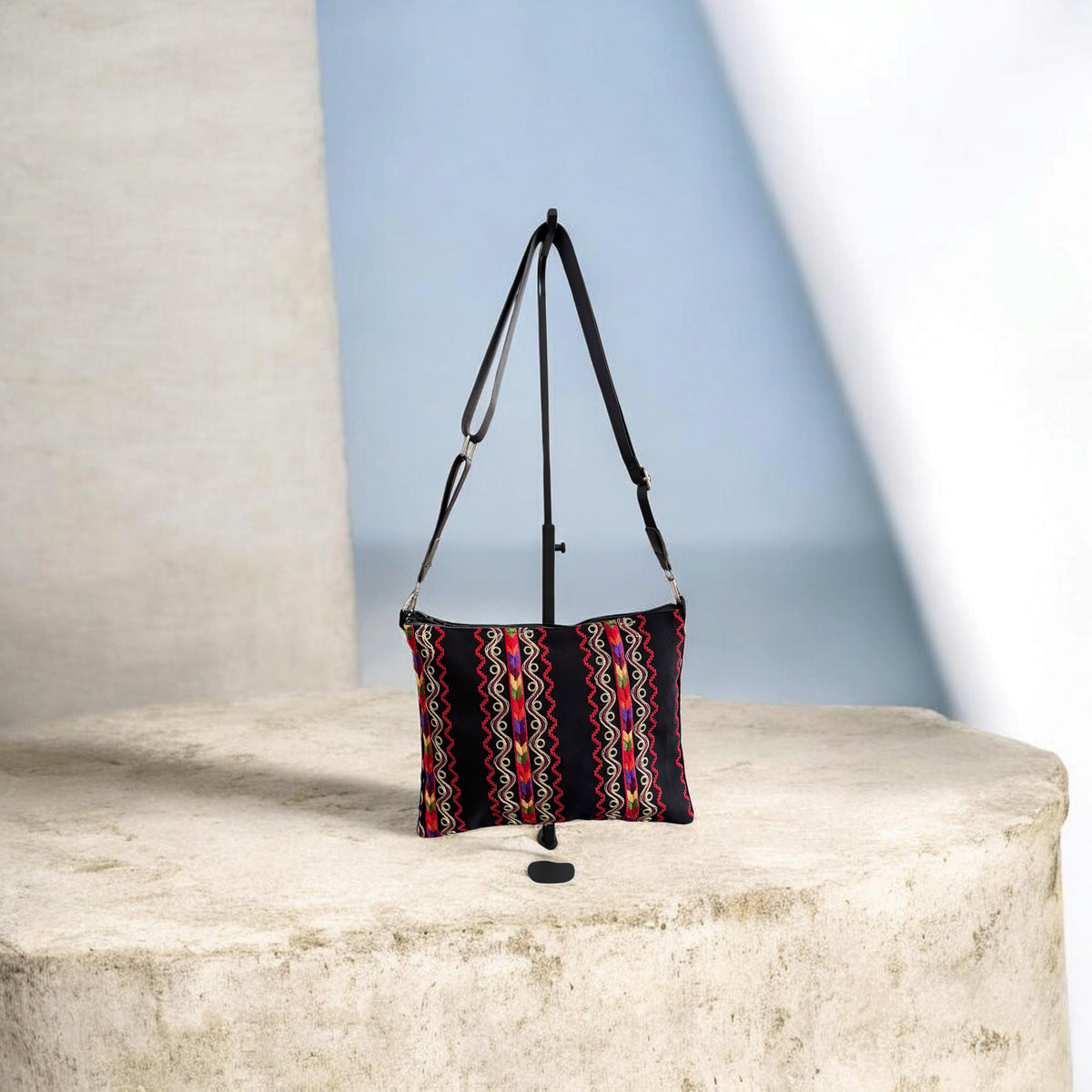 Sinsal Crossbody with vertical embroidered bands, hanging from its extended black crossbody strap.