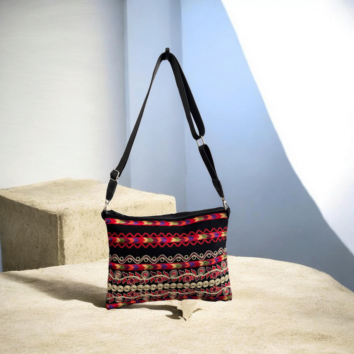 Sinsal Crossbody with horizontal floral embroidery and circular trim, shown with its black strap extended.