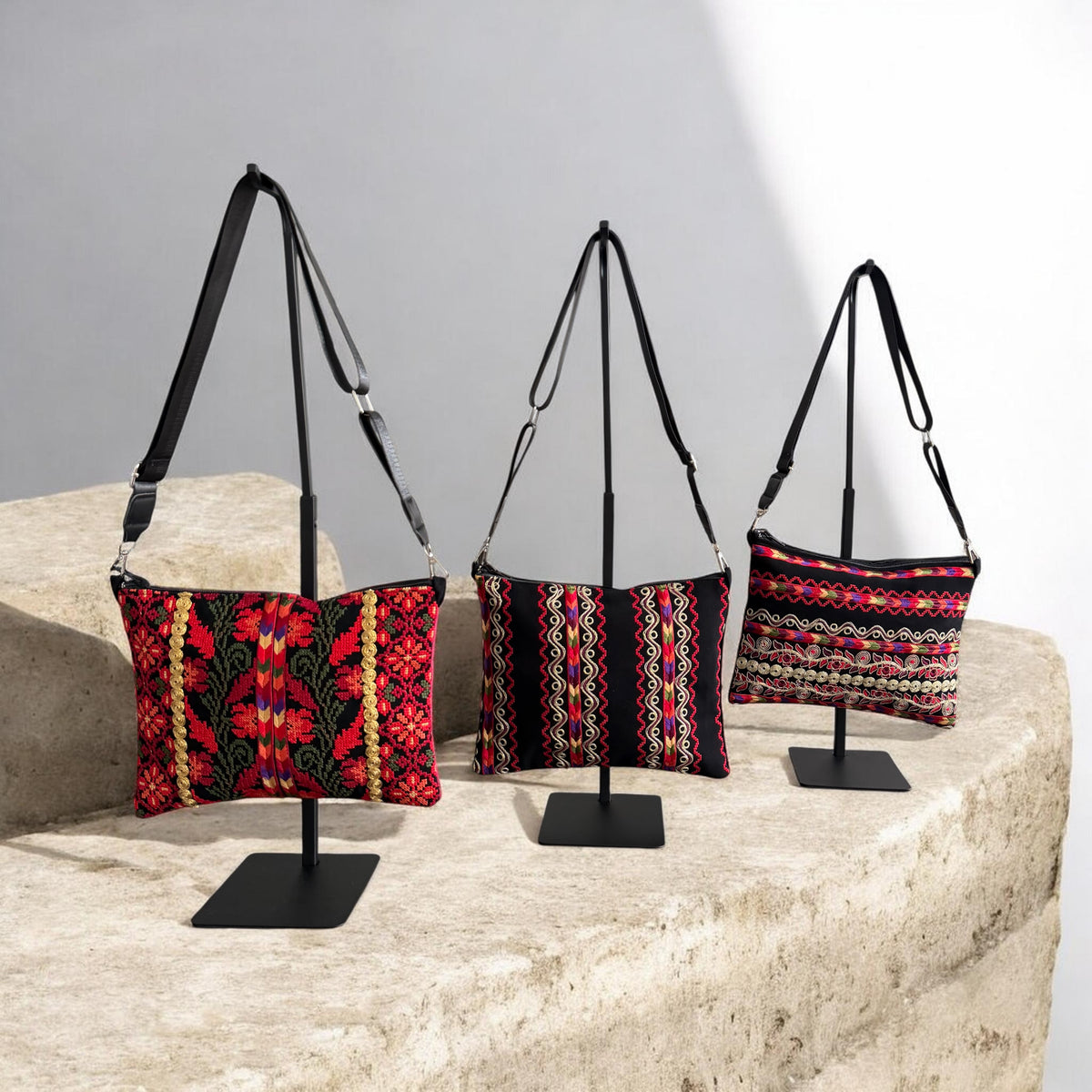 Three Sinsal Crossbody bags with red floral and multicolor striped embroidery, displayed with black straps.